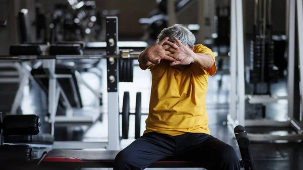 Senior strong man stretch hands in gym