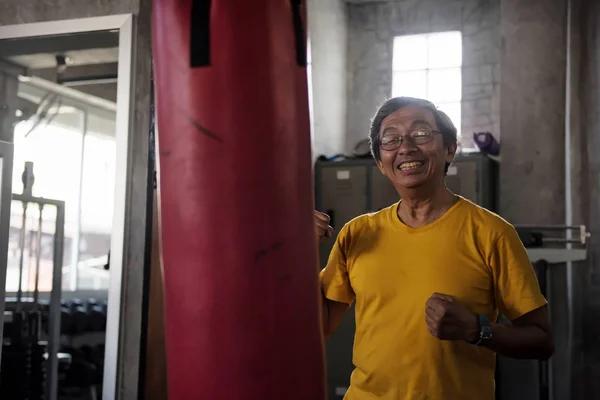 old man practice Thai boxing in gym
