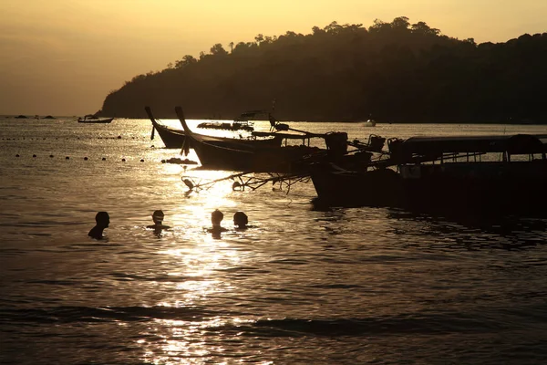 シルエットの人々は タイのサトゥン島のコ リペで日没時に長い尾の木のボートの近くのアンダマン海の動きのシーンで泳いでいます 抽象的で旅のランドマーク — ストック写真