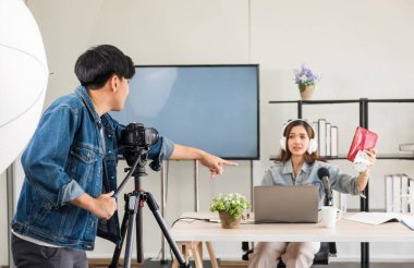 Sahne arkası konsepti. Çekici Asyalı kadın blogcu podcaster 'ın canlı yayınından önce kameraman kurulumu stüdyo ışıklandırmalı. Yayın vlogger, internet etkileyiciName.