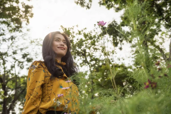 黄色のヴィンテージの衣装の美しい魅力的なアジアの日焼けの女の子の肖像は 日没の縁光と春の公園で花の庭の香り 女の子はテキストのためのスペースで休暇中に新鮮な空気 リラックスしてリフレッシュを取得します — ストック写真