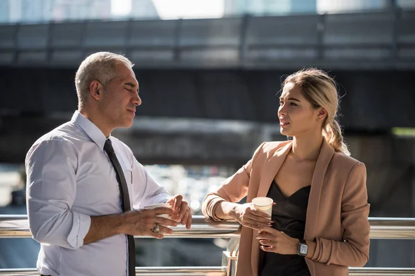 Business team discussion of senior old boss manager and young American secretary worker during coffee break. American businessman and  business woman talk about business informal talk at urban city.