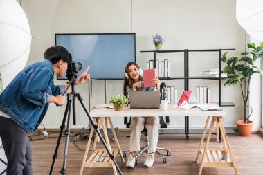 Sahne arkası konsepti. Çekici Asyalı kadın blogger podcaster stüdyo ışıklandırması ile çevrimiçi güzellik içeriğini canlı yayınlamadan önce kameraman kurulumu. Nüfuzlu yayıncı vlog kaydedici,