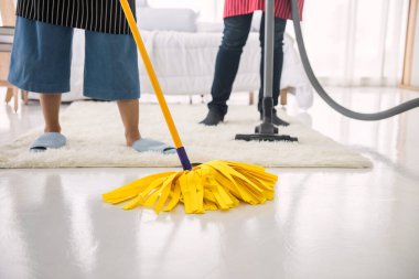 Çift elektrikli süpürge ve paspas kullanarak halı temizliyor ve yatak odasının zemininde fotokopi alanı var. Hijyen yaşam tarzı konsepti. Hafta sonu ev işi. Yeni eve ya da daireye taşındıktan sonra temizlik.