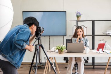 Sahne arkası konsepti. Stüdyo ışıklandırmalı güzel Asyalı kadın blogcunun canlı yayınından önce videoyu kaydetmek için kameraman testi. Yayın vlogger, internet etkileyiciName.