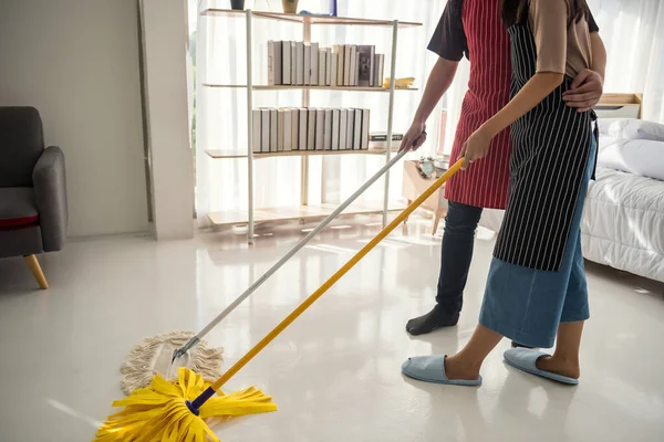 happy couple clean home bedroom by using vacuum cleaner and mop. Hygiene and health care lifestyle concept. Housework during weekend. Cleansing after moving to new home or apartment.