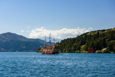 Hakone Gölü 'ndeki Hakone Tapınağı' nın kırmızı torii kapısından Fuji Dağı 'nın arka planına sahip kırmızı korsan turist gezisi. Korsan gemisi Hakone 'nin en ünlü turist dilek listelerinden biridir..