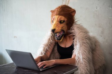 Aslan maskeli kadın mafya ajanı uyuşturucu veya eroin kaçakçılığı için dizüstü bilgisayar kullanıyor. Gri ticarette internet üzerinden uyuşturucu satışı. Yasalara aykırı suistimal, suç ve uyuşturucu kavramı.