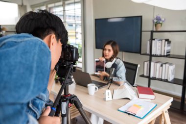 Video ya da profesyonel dijital kameraman, güzel Asyalı kadın blogger podcaster 'ının canlı yayınını çekmeye hazır olun. çevrimiçi günlük veya web sitesi içeriği için yayın.