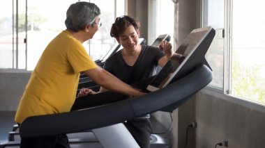 Spor salonunda kişisel antrenörle birlikte koşu bandında 60 'lı yaşlarda Asya' nın son sınıf erkek kardiyo egzersizi. Emekli yaşlı adam ya da yaşlılar için vücut geliştirme ve sağlık sporları eğitimi.