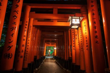 Torii kapısı, Japonca metin kemer işaretli ve geceleri Fushimi Inari Taisha türbesini aydınlatan bir fener. Kansai, Kyoto, Japonya 'daki binlerce Torii Gates için seyahat yeri