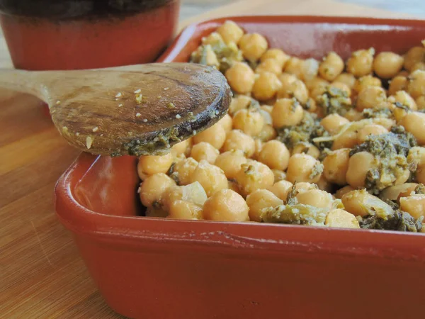 Tahta kaşıkla seramik tabakta ıspanaklı nohut.