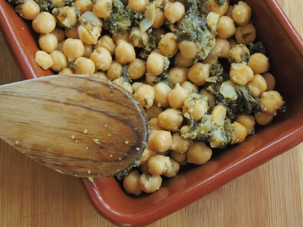 Tahta kaşıkla seramik tabakta ıspanaklı nohut.