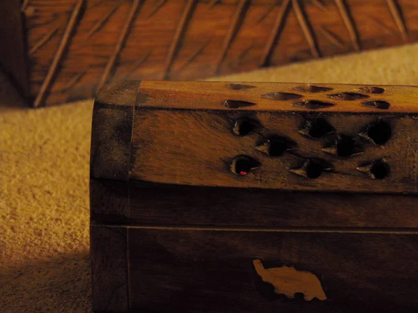 Incense box on a rustic table with a trunk of wood.