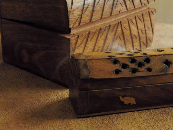 Incense box on a rustic table with a trunk of wood.