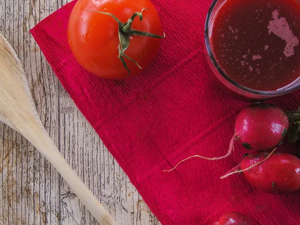 Turp suyu yanında yeşil bir peçete pembe bir arka plan üzerinde domates ile.