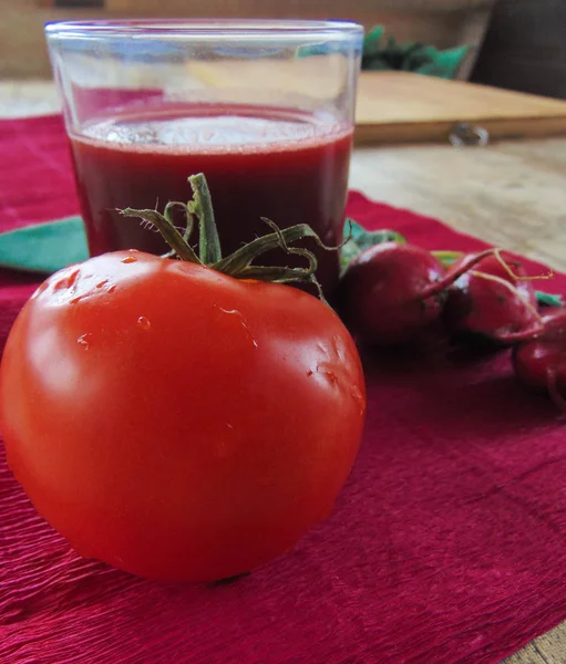 Turp suyu yanında yeşil bir peçete pembe bir arka plan üzerinde domates ile.