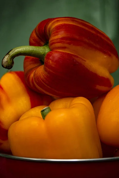 Gelbe Und Gestreifte Paprika Einem Roten Colandar Mit Grünem Hintergrund — Stockfoto