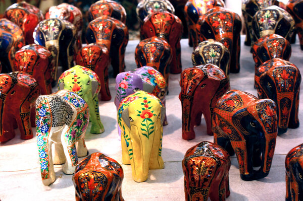 Colorful elephants Souvenirs of different colors with their trunk up, elephant toys in Indian market. Souvenirs made of wood, painted with colorful ornaments.