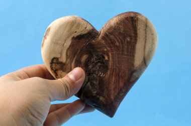 Kadın el ahşap bir kalp mavi arka planı tutarak