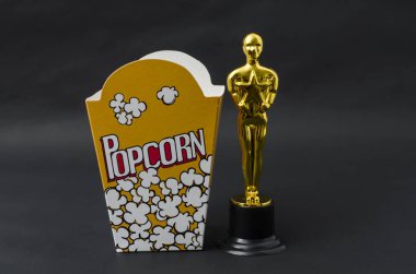 Xalapa, Veracruz, Meksika - 14 Şubat 2019: Sarı patlamış mısır kutusu ve plastik oscar Ödülü karşı siyah arka plan