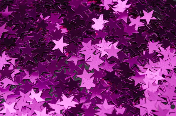 Random stars shine on a black background. Confetti pink stars background