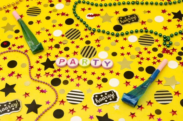 パーティのトップ ビューの装飾 カラフルな文字 プラスチック ネックレス 党ブロワ 黄色の背景に円や星紙吹雪から作られたパーティのワード — ストック写真