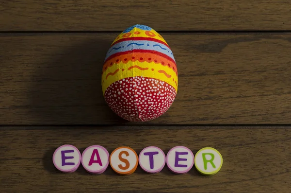 Easter made from colorful letters and colorful decorated easter egg on wooden background