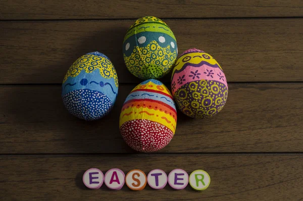Easter made from colorful letters and colorful decorated easter eggs on wooden background