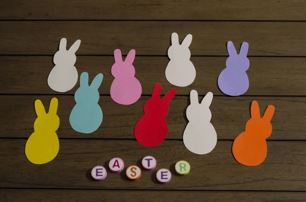 A bunch of colorful paper bunnies and easter made form colorful letters on wooden background