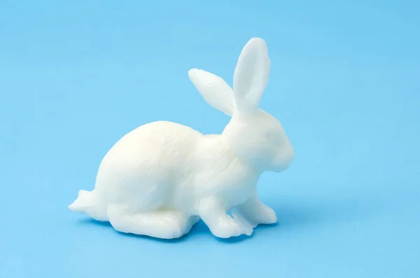 White toy little bunny isolated on blue background. Toy bunny rabbit on blue background