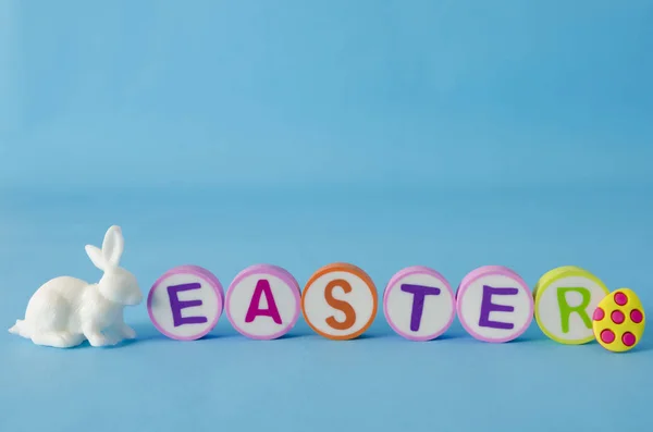 Easter made from colorful letters and white little bunny on blue background. Easter decoration