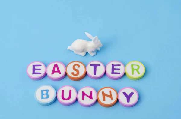 Easter bunny made from colorful letters and white little bunny on blue background. Easter decoration