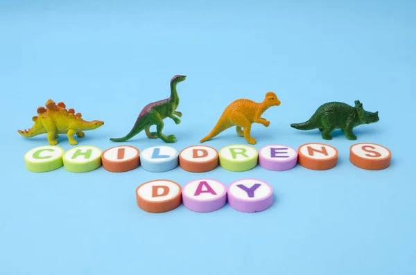 Kindertag Aus Bunten Buchstaben Und Dinosaurier Plastikspielzeug Vor Blauem Hintergrund — Stockfoto