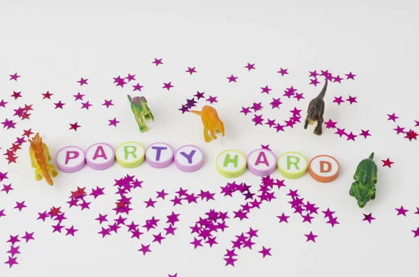 カラフルな文字 おもちゃの小さな恐竜や星の紙吹雪から作られたパーティーハード白い背景に — ストック写真