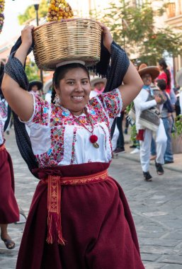 Oaxaca, Oaxaca, Meksika- Temmuz 6, 2019: Genç kadın Convite sırasında renkli çiçeklerle süslenmiş bir sepet taşıyan geleneksel giysiler ile giyinmiş, oaxaca Guelaguetza adlı büyük bir geleneksel partiye davet için yapılan bir parti, Meksika