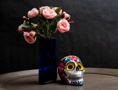 Elle boyanmış kafatası ve bir buket gül siyah arka planda vazoda