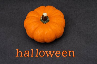 Küçük turuncu balkabağı ve cadılar bayramı siyah arka planda plastik turuncu harflerden yapılır.