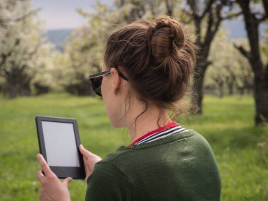 Açık havada onun ebook üzerinde okuma genç bir kadın arkadan görünüş