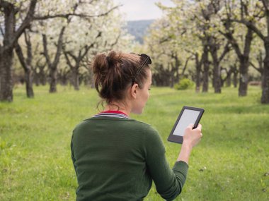 Açık havada onun ebook üzerinde okuma genç bir kadın arkadan görünüş