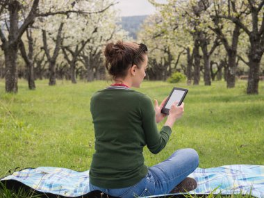 Açık havada onun ebook üzerinde okuma genç bir kadın arkadan görünüş