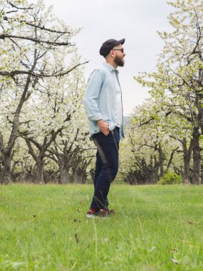 Sakallı hippi adam rahat kıyafetler ve doğada yürüyüş zevk güneş gözlüğü takmış