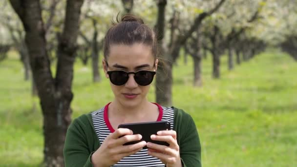 彼女の携帯電話で写真を撮ってのサングラスをかけた若い白人女性 — ストック動画