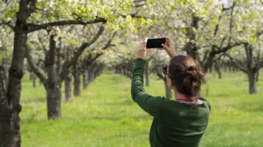Arkadan Görünüş onun smartphone ile fotoğraf çekmek doğa genç bir beyaz kadın