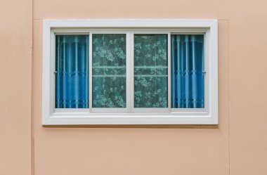 Uv perdesi ve dış görünümden açık kahverengi ev duvarı ile modern pencereler.