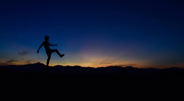 Günbatımında yürüyen bir adamın silueti.