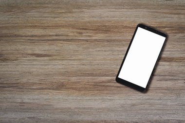 Mobil akıllı telefon, tahta masa arkasında boş ekran ve fotokopi alanı var. Yukarıdan aşağıya