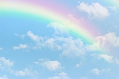 Mavi gökyüzünde beyaz bulutlu bir gökkuşağı.