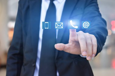 Bağlantı kur. İş adamı el ile simgeye basar (telefon, posta, adres).