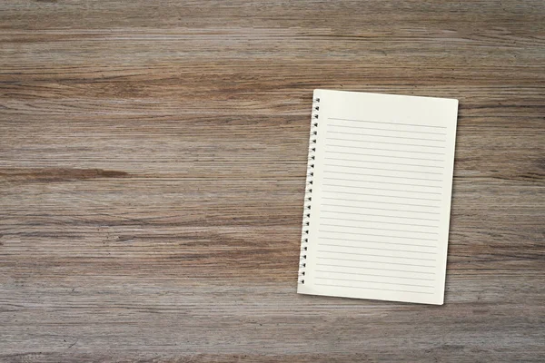 コピースペースと木製の机の背景に空白の白いノートパッド トップダウン — ストック写真